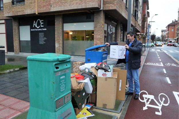 Un vecino de Lugones deposita una caja en un contenedor de reciclaje de papel y cartón. 
