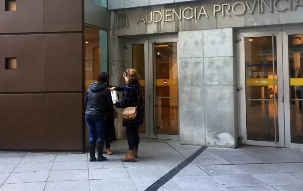 La víctima, a la izquierda, conversa con su acompañante y su abogada a la puerta de la Audiencia, en Oviedo. 