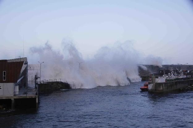 Una ola salta el espigón del puerto pesquero de Llanes, donde se quedaron cuatro barcos que no accedieron a la dársena interior. 