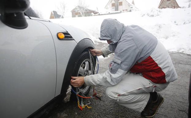 Un hombre coloca las cadenas a un turismo para circular por carreteras nevadas