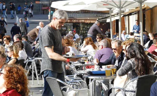 Un camarero atienda a turistas en una terraza.