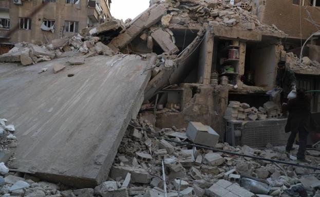 Civiles observan un edificio derruido tras un bombardeo.