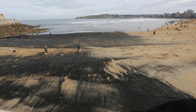 La playa de San Lorenzo, ennegrecida por el carbón que procede del 'Castillo de Salas'. 