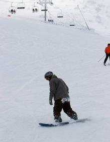 Imagen secundaria 2 - Arriba, la nieve en Sotres. Abajo a la izquierda, un niño en trineo; a la derecha, un hombre practicando snowboarding.