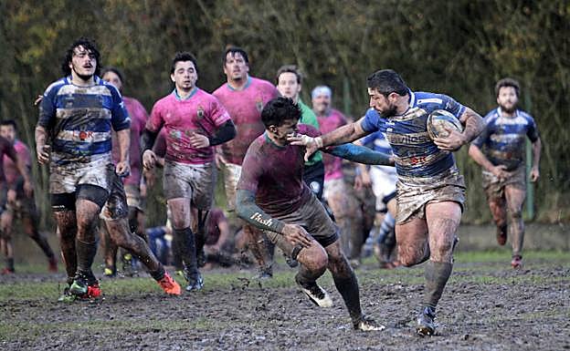 Un partido, con los jugadores muy embarrados, en el campo del Naranco.