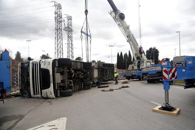 Operarios del servicio de grúas tratan de retirar el camión de la vía. 