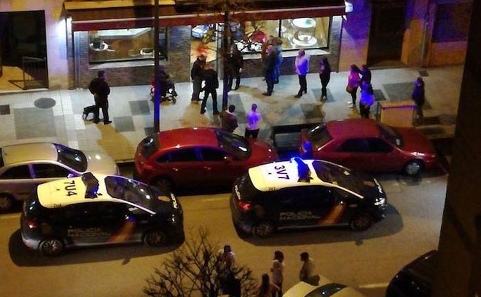 Dos patrullas de la Policía Nacional, junto a clientes del bar y vecinos, a las puertas del local.