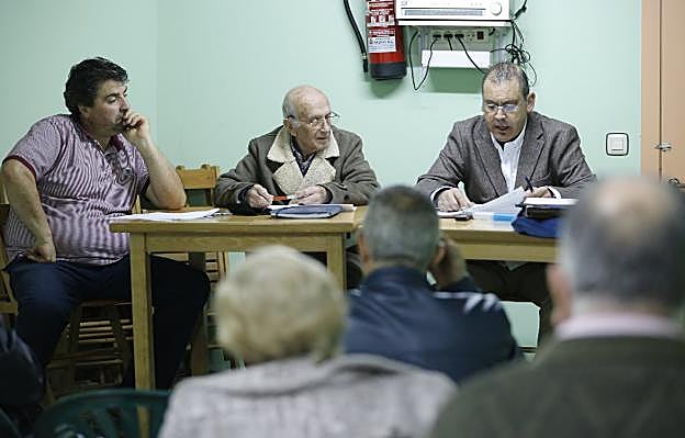 Ovidio Río preside la asamblea vecinal de Castiello de Bernueces, rodeado del secretario Alberto Ferreras, en plena intervención, y el tesorero Eduardo Argüelles. 