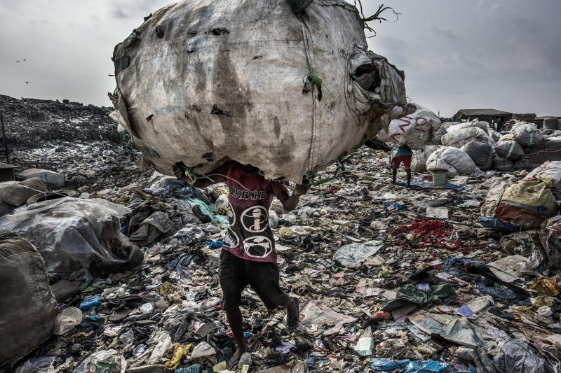 La foto muestra a un hombre mientras carga un enorme lomo de botellas recogidas para su reciclaje en el vertedero de Olusosun en Lagos, Nigeria, el 21 de enero de 2017. 
