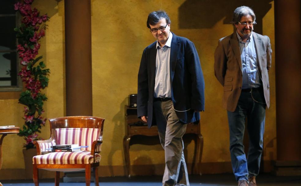 Javier Cercas entra en el escenario del Campoamor, ante el fondo de 'La malquerida', con Arturo Téllez. 