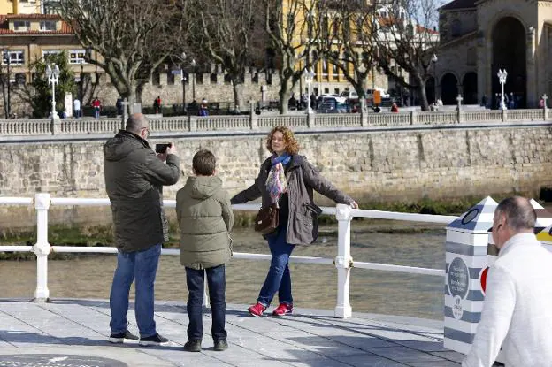 Una familia se fotografía en el paseo del Muro, con el campo Valdés al fondo. 