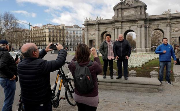 Varios turistas se fotografían ante la Puerta de Alcalá, en Madrid. 