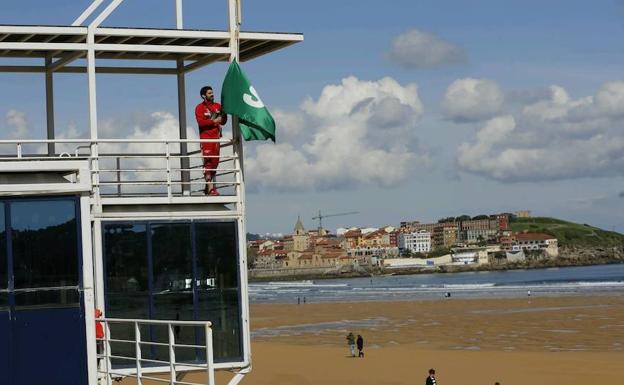 Un socorrista coloca la bandera verde que inaugura la temporada.