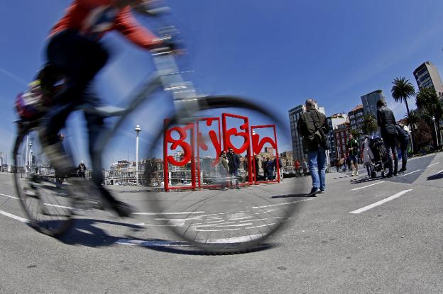 Gijón. Varios turistas disfrutan del buen tiempo en el Muelle. 