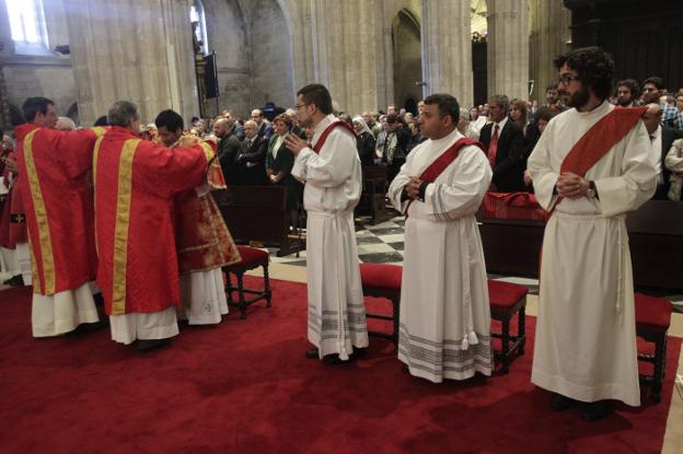 Los tres nuevos sacerdotes Emmanuel González, Allan Eduardo Cerdas y Ángel María Vilaboa, en primer plano, mientras ordenan a un diácono en la catedral de Oviedo. 