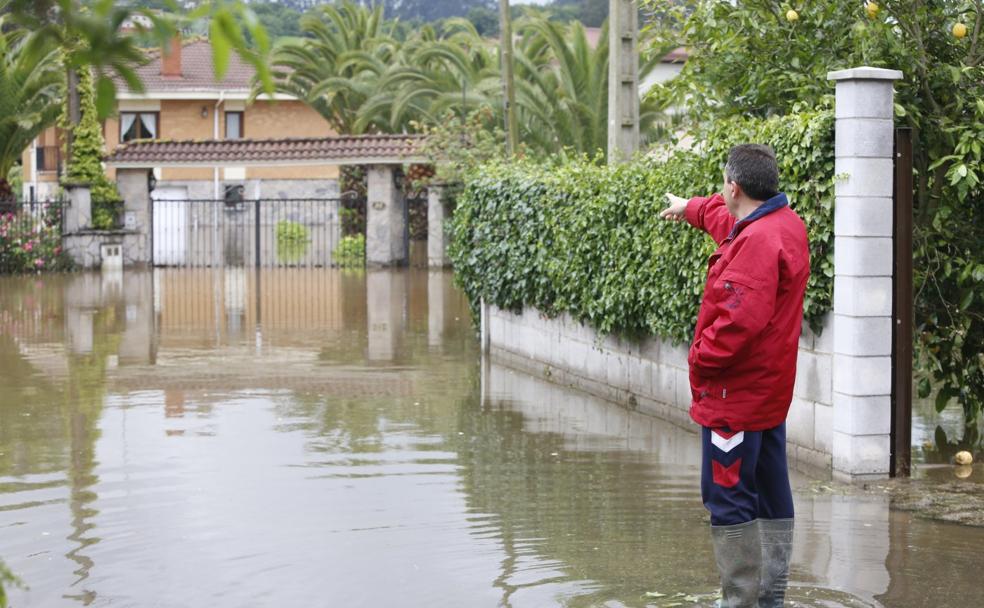 Un vecino de Porceyo, en Gijón, contempla la entrada de su casa completamente inundada. 