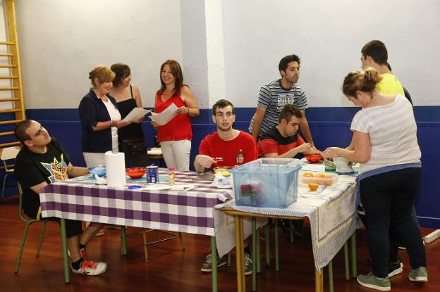 Violeta Menéndez, Cristina González y Carmen de la Rosa, al fondo, mientras en la mesa Sergio, Cristian e Ismael preparan la mousse ante la mirada de los coordinadores, Marcos González y Begoña Donarie, que exprime las naranjas con Yeri. 