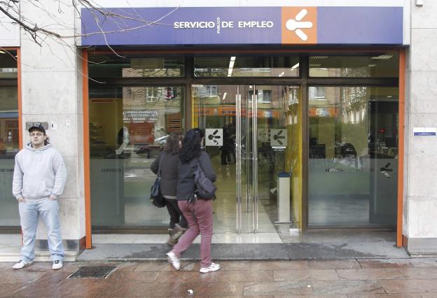 Una mujer accede a una de las oficinas de empleo que el Principado tiene en Oviedo mientras un joven espera en la puerta. 