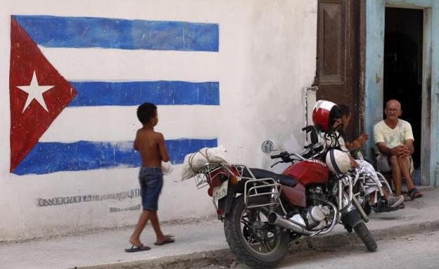 Un niño pasa junto a una pintura de la bandera cubana en una pared de La Habana. 