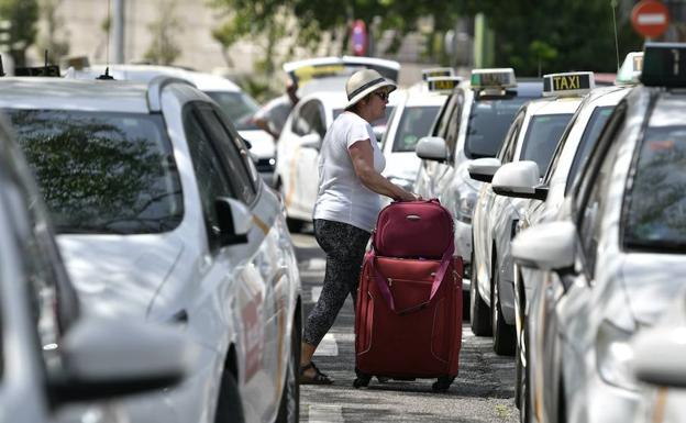 Una viajera pasa entre los taxis aparcados. 