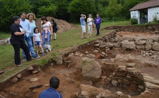 Margarita Fernández Mier (izquierda) explica los hallazgos a los primeros visitantes del yacimiento este verano.