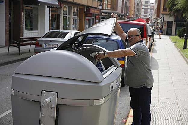 Un vecino deposita una bolsa en uno de los nuevos contenedores en El Entrego. 