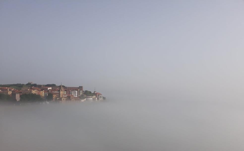 La playa de San Lorenzo, cubierta de niebla. A la izquierda, San Antolín, en Llanes. 