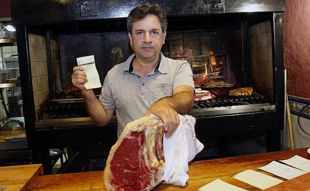 Joaquín Fernández, propietario de El Mancu, sostiene la factura del día del 'simpa', que incluía un chuletón de casi tres kilos. 