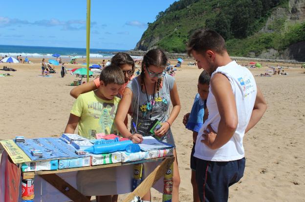 Cuatro jóvenes rellenan, a pie de playa, la encuesta realizada por la fundación a los usuarios del arenal. 