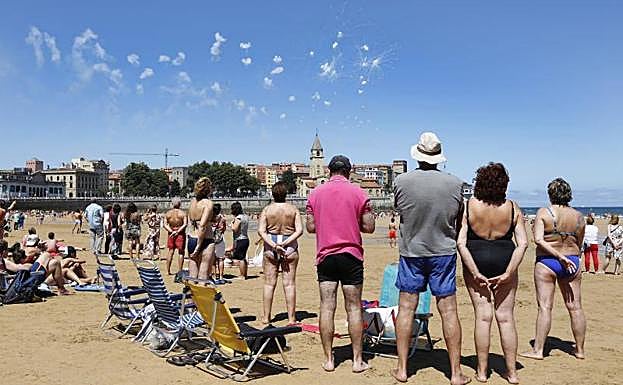 Numerosos bañistas observan desde San Lorenzo El Restallón sobre la iglesia de San Pedro. 