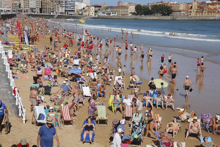 El sol y el calor anunciados para este fin desemana han llenado las playas de Asturias. En San Lorenzo, por ejemplo, miles de personas disfrutan del arenal y del paseo del Muro.