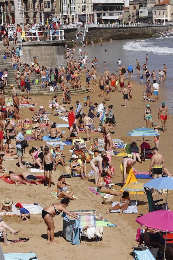 El sol y el calor anunciados para este fin desemana han llenado las playas de Asturias. En San Lorenzo, por ejemplo, miles de personas disfrutan del arenal y del paseo del Muro.