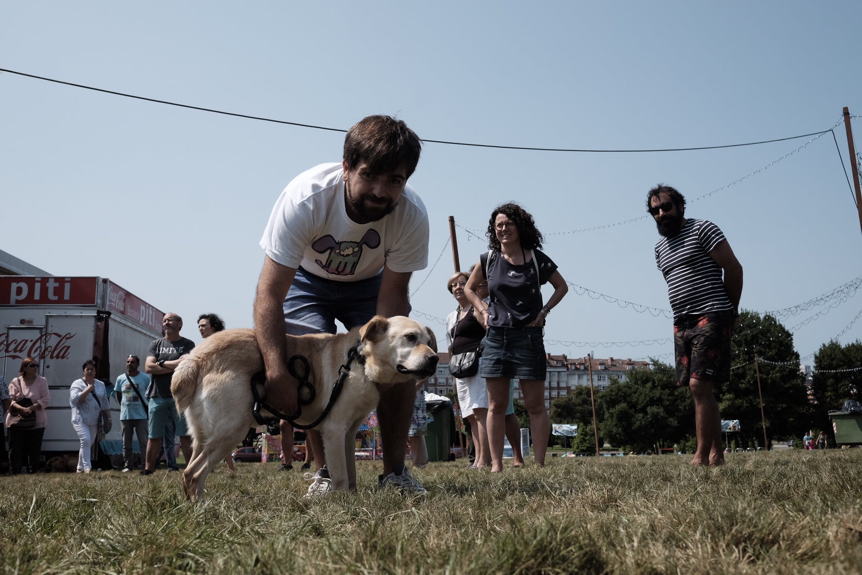 19 perros, del albergue de Serín, con pañuelo rojo sobre el cuello, a los que se busca un hogar, desfilaron por el recinto habilitado en Los Pericones, donde el barrio de Contrueces celebra su fiesta