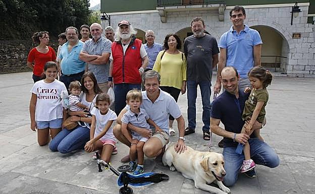 Miguel Ángel Fernández, alcalde de Caso, con camisa de cuadros, rodeado de vecinos frente al Ayuntamiento.