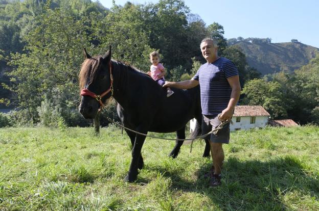 El ganadero José Miguel González, 'Pepín el de la Riera', con 'Xana' y su nieta de un año Jade. 