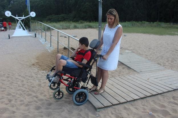 Raquel Cuevas accede a la playa de La Ñora con su hijo, Gabriel Covián. 