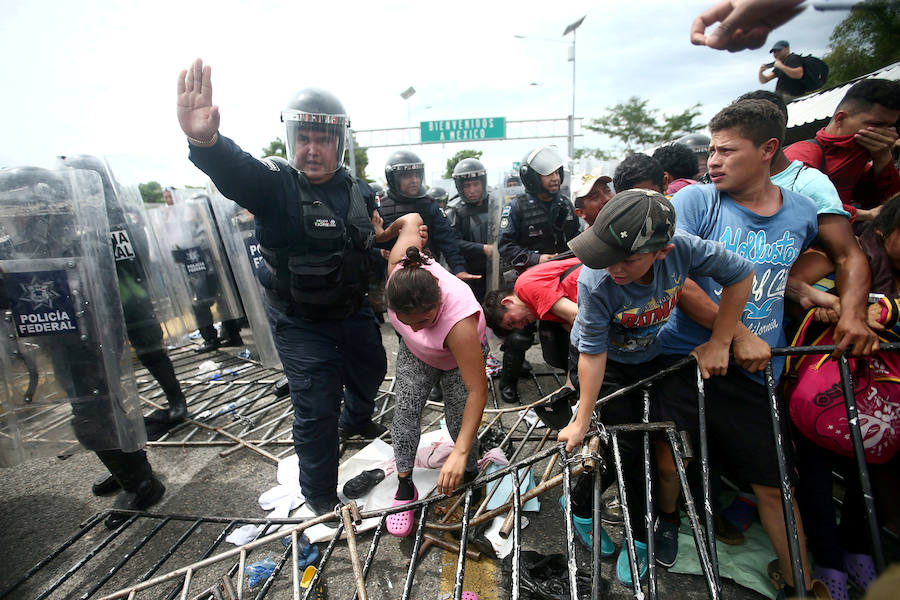 Un policía ayuda a una migrante hondureña, parte de la caravana que intenta llegar a los Estados Unidos, mientras asalta un puesto fronterizo para cruzar a México.