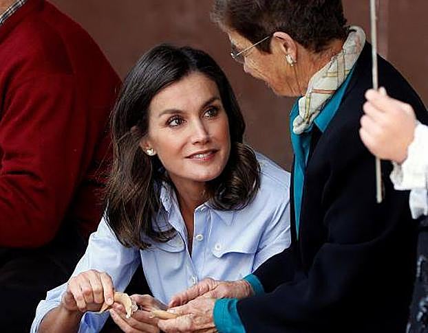 Una mujer enseña a la Reina a esbillar fabes.