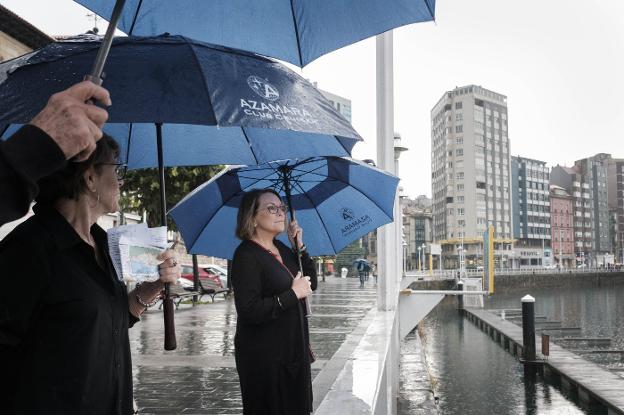 Turistas bajo la lluvia, ante el muelle del Puerto Deportivo gijonés. 