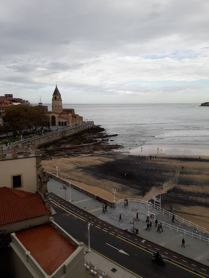 La playa de San Lorenzo de Gijón ha amanecido cubierta por una nueva mancha de carbón. A pesar de que no es una situación desconocida para los vecinos, muchos no han dudado en inmortalizar la estampa.