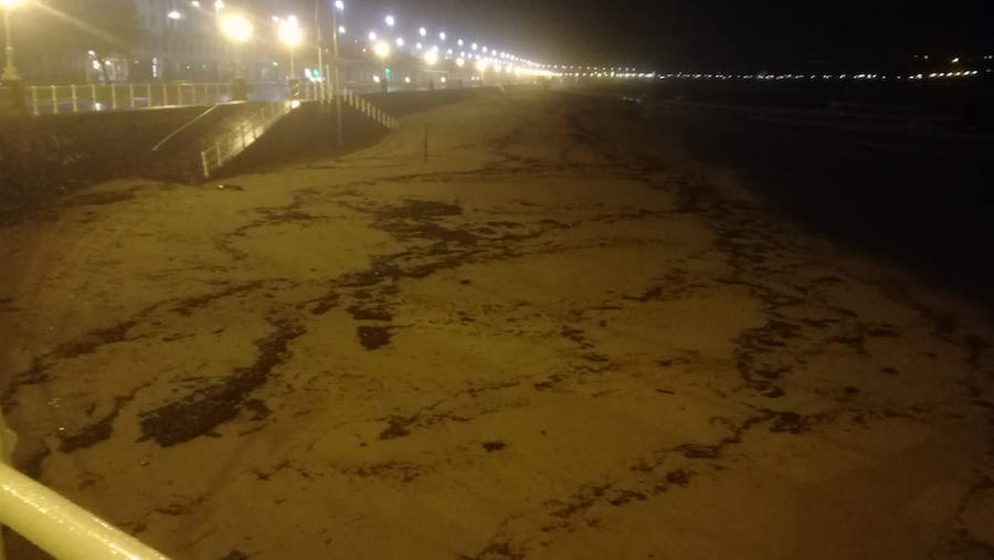 La playa de San Lorenzo de Gijón ha amanecido cubierta por una nueva mancha de carbón. A pesar de que no es una situación desconocida para los vecinos, muchos no han dudado en inmortalizar la estampa.
