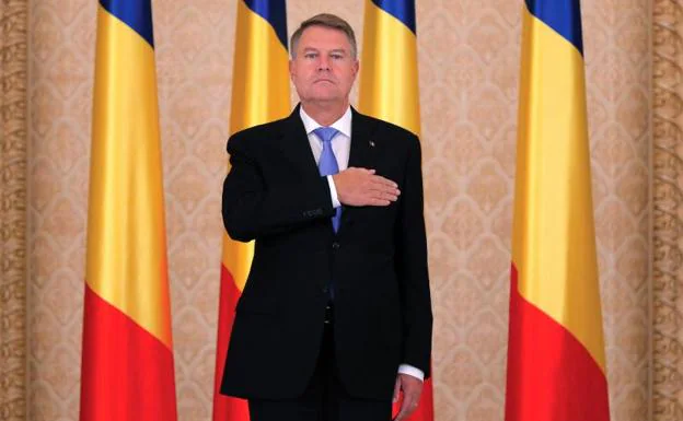 El presidente rumano, Klaus Iohannus, escucha su himno nacional.