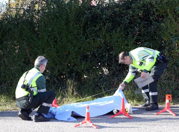 Dos agentes ante el cuerpo del motorista fallecido. 