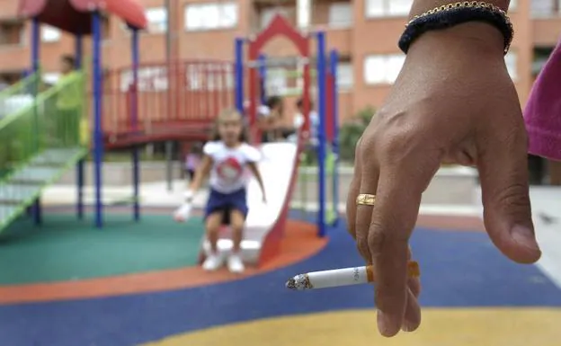 Una mujer fuma en un parque infantil.