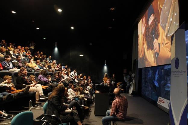 Niños y padres escuchan al L'Anguleru por videoconferencia en el Acuario. 