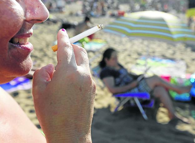 Una mujer fuma un cigarrillo en la playa de San Lorenzo. 