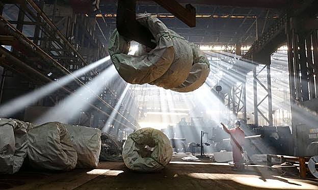 Un trabajador dirige la labor de elevado de una bobina de acero en la fábrica del grupo Dongbei Special Steel, en Dalian, China. 