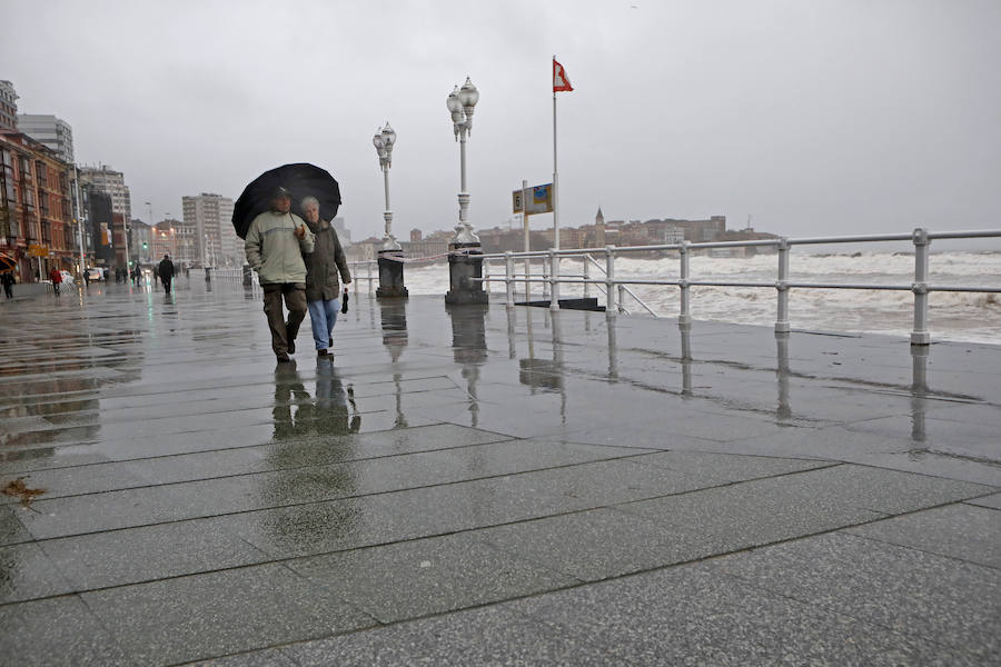 Un río Piles a punto de desbordarse, aguas turbias, o el oleaje rompiendo con fuerza en las escaleras del Muro son algunas de las imágenes que deja la pleamar esta tarde en Gijón
