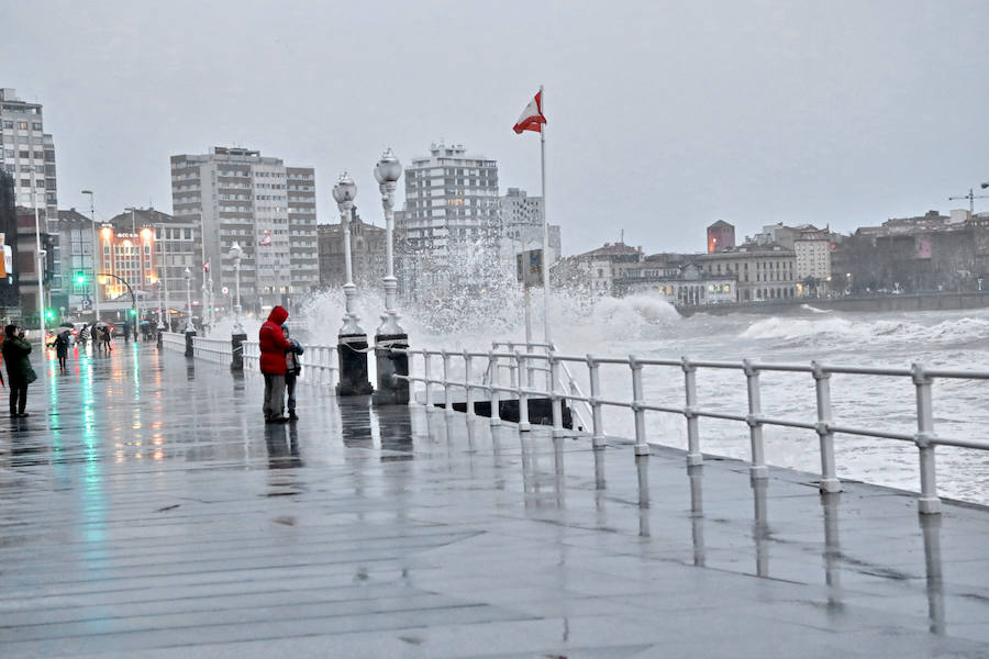 Un río Piles a punto de desbordarse, aguas turbias, o el oleaje rompiendo con fuerza en las escaleras del Muro son algunas de las imágenes que deja la pleamar esta tarde en Gijón