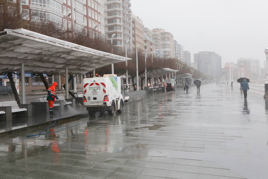 El paseo gijonés del Muro ha amanecido con algunas de sus escaleras cerradas debido a los daños causados por el temporal de lluvia y viento. Operarios de Emulsa han procedido a la limpieza de la arena depositada en el paseo tras la pleamar.